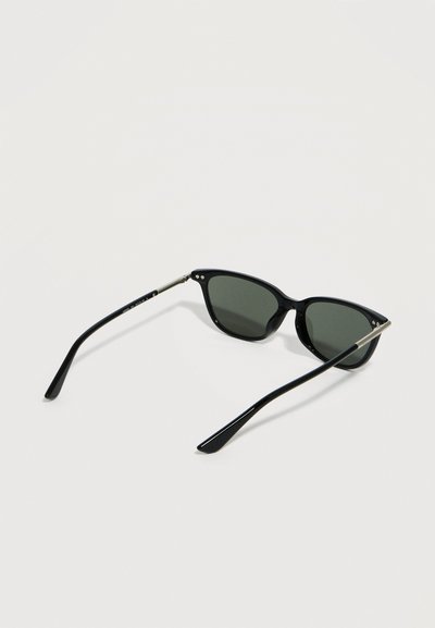 Μαύρα γυαλιά ηλίου σε στυλ wayfarer με σκοτεινούς φακούς και λεπτές ασημένιες μεταλλικές λεπτομέρειες στα πλαϊνά, ανοιγμένα και τοποθετημένα πάνω σε λευκή επιφάνεια.