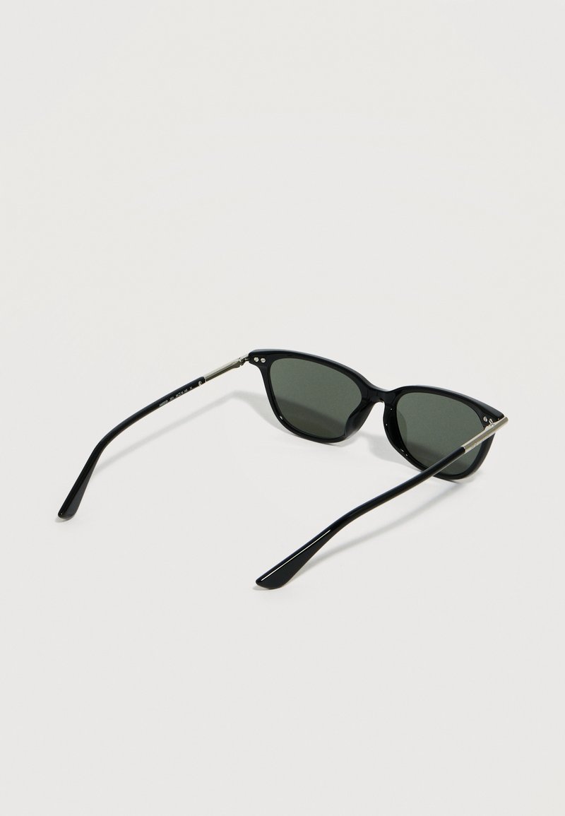 Black wayfarer-style sunglasses with dark lenses and thin silver metal accents on the temples resting open on a white surface.
