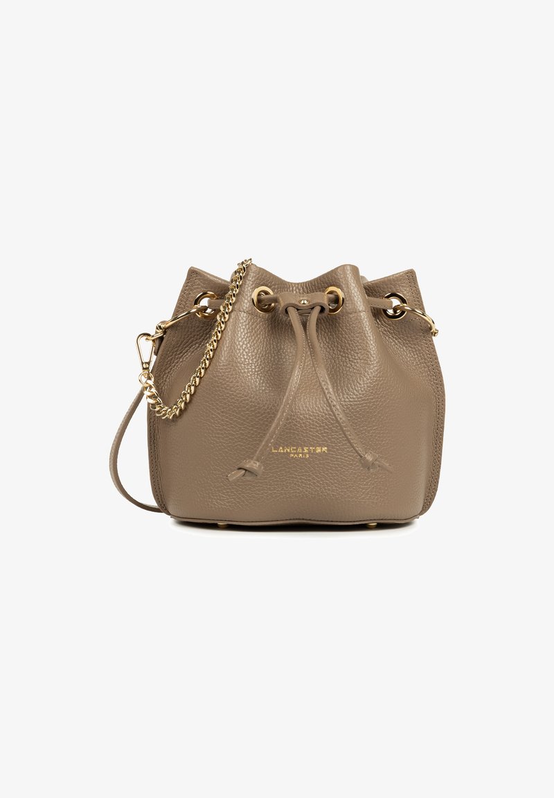Sac seau en cuir taupe avec une finition texturée, quincaillerie dorée, fermeture à cordon, et une sangle en chaîne détachable. Logo sur le devant.