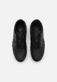 Svarta lädersneakers för golf med låg design, perforerat tåparti, platta svarta snören och vit gummisula. Har logotyp p å tungan.