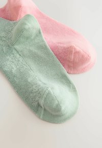 Två par ankelsockor: ett par i mjuk rosa och ett par i mintgrön, med ett texturerat mönster längs sidorna och en slät finish.