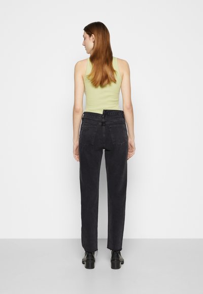 Black high-waisted jeans with a straight leg design, frayed hem, and two back pockets, paired with a fitted light green tank top.