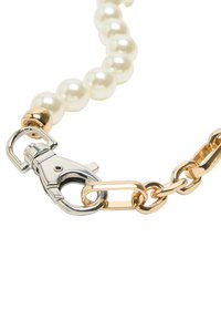 Łańcuszek z pereł z akcentami ze złotego i srebrnego metalu. Posiada srebrną zapięcie typu homar oraz wydłużone złote ogniwa, tworząc teksturowany wzór.