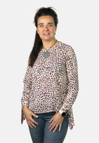 Blusa ligera de manga larga con base en color crema y estampado de leopardo burdeos. Decorada con un gran collar y mangas atadas.