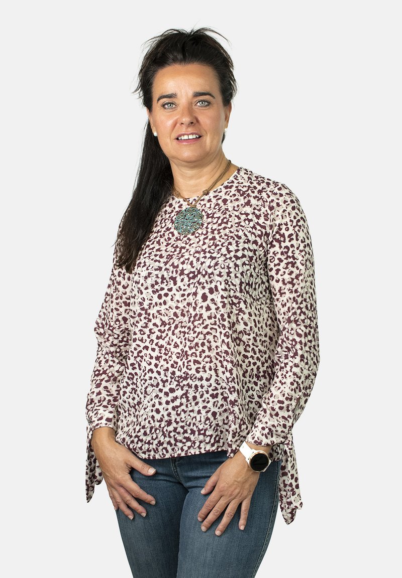 Blusa ligera de manga larga con base en color crema y estampado de leopardo burdeos. Decorada con un gran collar y mangas atadas.
