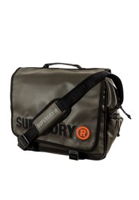 Sac messager imperméable gris avec une sangle noire, arborant un branding "SUPERDRY" orange et noir et une poche latérale zippée.