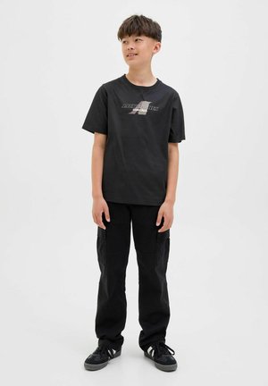 Zwarte katoenen t-shirt met een grafisch logo, gecombineerd met zwarte cargobroeken met zijkanten zakken en gedragen met zwarte sneakers.
