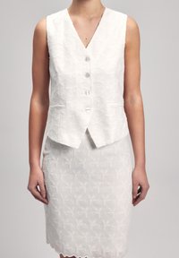 White sleeveless vest with floral texture and five buttons, paired with a matching skirt featuring a scalloped hem and similar pattern.