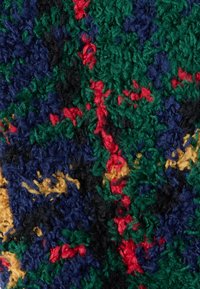 Tessuto strutturato con colori vivaci: blu navy, verde, rosso, nero e giallo. Presenta una trama soffice e pelosa e un motivo astratto multicolore.