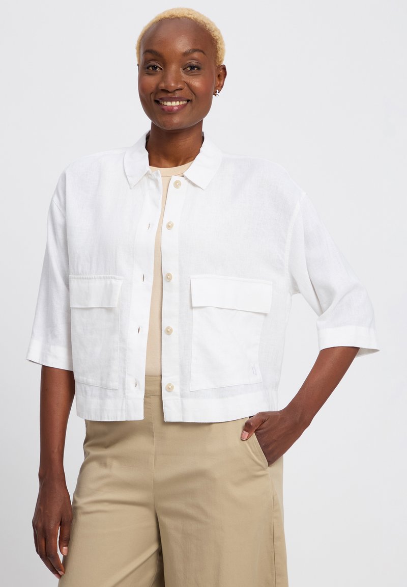 Witte linnen cropped jacket met een kraag, grote voorklep zakken en driekwart mouwen. Gladde textuur en knoopsluiting aan de voorkant.