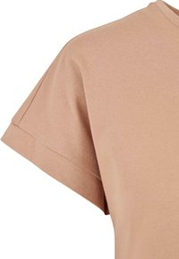 Hellbraunes Kurzarm-T-Shirt mit einem schlichten Rundhalsausschnitt. Hergestellt aus weichem Baumwollstoff, der eine glatte Textur und minimale Nähdetails aufweist.