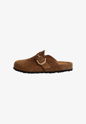 Braune Wildlederclogs mit einem breiten Riemen und einer Metallschnalle, Kork-Zwischensohle und einer schwarzen Gummisohle, die eine glatte, strukturierte Oberfläche aufweist.