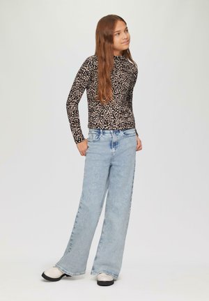Zwarte long-sleeve top met een klein bloemmotief, gecombineerd met lichtblauwe wijde spijkerbroeken en zwart-witte instapschoenen.