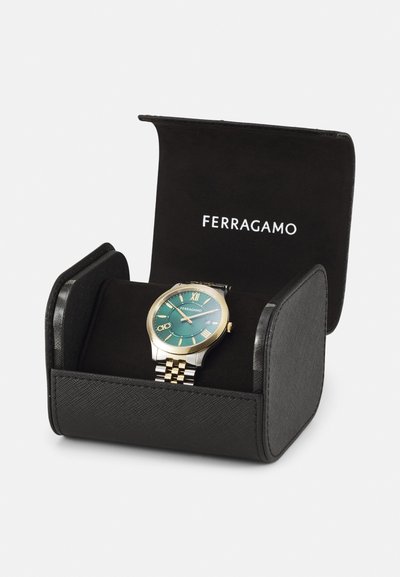 Round Ferragamo watch with teal dial, gold accents, silver and gold-toned band, presented in a black cushioned display box.