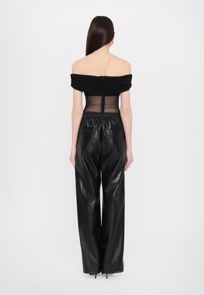 Melns off-the-shoulder tops ar ručētu audumu un caurspīdīgām paneļām, kombinēts ar augsto vidukli melnām ādas biksēm ar spīdīgu apdari.