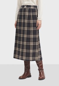Rutig midi kjol i marinblått och beige, med veck och knappstängning i midjan, ihop med bruna knähöga stövlar.