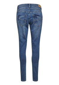 Jeans ajustados de mezclilla en tono azul, con un lavado medio, sutil desteñido y dos bolsillos traseros con costuras decorativas.