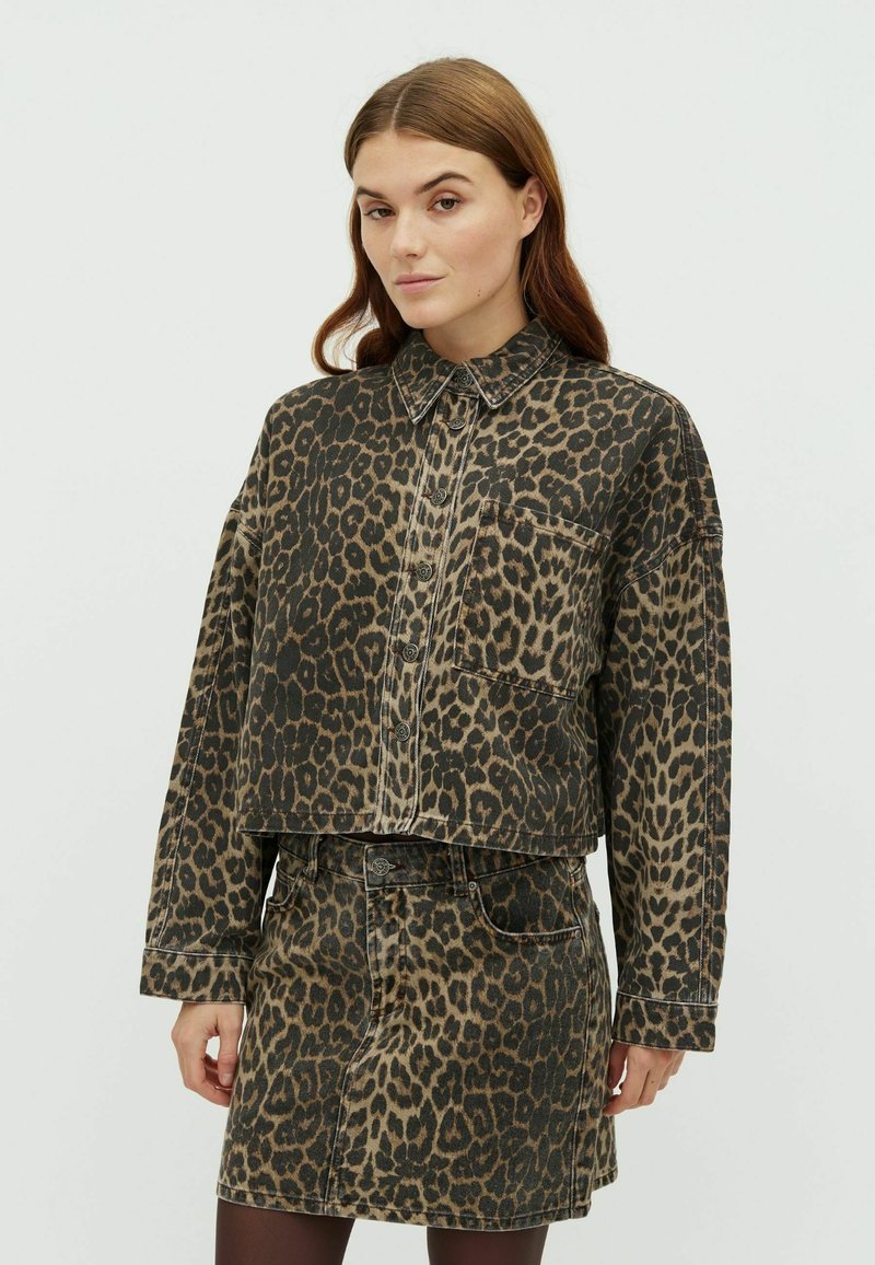 Džínová bunda s leopardím vzorem, s límečkem, dlouhými rukávy a předními knoflíky. Spárováno s odpovídající mini sukní, obě v hnědých a černých odstínech.
