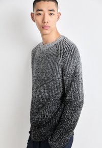 Maglione lavorato a maglia spessa in tonalità di grigio, con scollatura tonda e polsini a coste, caratterizzato da un motivo testurizzato e una vestibilità ampia.