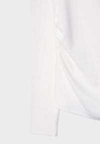 Witte top met lange mouwen en een gladde textuur, met gathered details aan de zijkant en een recht afgesneden mouw. Eenvoudig en minimalistisch ontwerp.