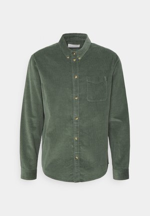 Green corduroy button-up shirt with long sleeves, collar, front pocket, and gold buttons. Features a textured fabric and curved hem.