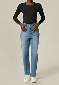 Černý bodysuit s dlouhými rukávy v kombinaci s světle modrými rovnými džíny s vysokým pasem a bílými teniskami, s čistým designem a jednoduchými liniemi.