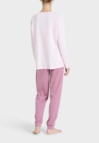Maglietta rosa a maniche lunghe con scollatura rotonda abbinata a pantaloni da pigiama leggeri a fantasia rosa. I pantaloni hanno polsini elasticizzati e una vestibilità comoda.