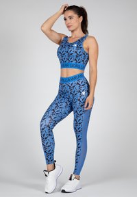 Blauwe sportieve twee-delige set met een crop top en legging met een zwart abstract patroon, aangevuld met een blauwe tailleband.