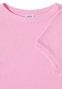 Pull tricoté léger rose avec de petits trous de ventilation et un col rond, montrant une partie de la manche courte et l’étiquette de la marque.