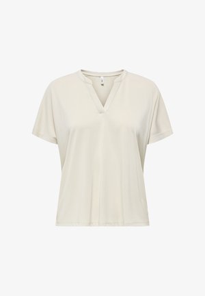 Mujer con camiseta crema de manga corta y escote en V y pantalones negros de pierna ancha, sosteniendo un bolso marrón oscuro texturizado con dos asas.