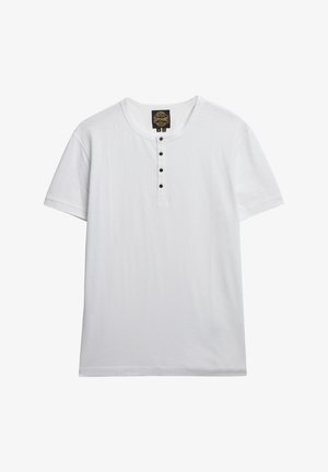 Biała krótko rękawowa koszulka wykonana z miękkiej bawełny, z okrągłym dekoltem i pięcioma czarnymi guziczkami na przedniej listwie.