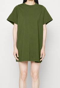 Olivgrön oversized t-shirt klänning i bomull med rund halsringning och korta ärmar, med en rak skärning och sidofickor vid fållen.