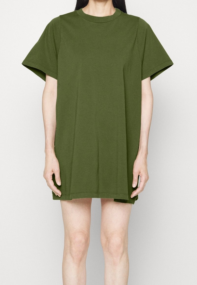 Olivgrön oversized t-shirt klänning i bomull med rund halsringning och korta ärmar, med en rak skärning och sidofickor vid fållen.