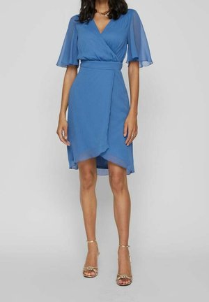 Niebieska sukienka kopertowa z falbanowymi rękawami, długość do kolan, miękka w dotyku. Podkreślona pasującym paskiem. W komplecie złote sandały.