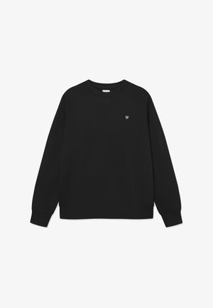 Melns džemperis, kas izgatavots no mīkstas auduma, ar apaļo izgriezumu, garām piedurknēm, ribota piedurknes un apakšmala, ar mazu emblēmu uz krūšu daļas.