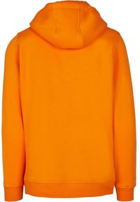 Sudadera naranja hecha de una tela suave, con capucha y puños acanalados. El diseño es sin costuras, sin logotipos ni adornos visibles.