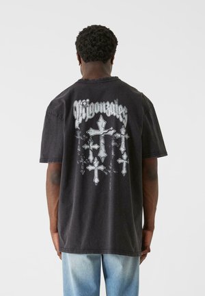 Black cotton t-shirt featuring large white cross graphics on the back, with a relaxed fit and slightly distressed edges.