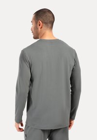 Graues Langarmshirt aus weichem Stoff, mit rundem Ausschnitt und lässiger Passform. Glatte Textur ohne sichtbare Muster oder Akzente.