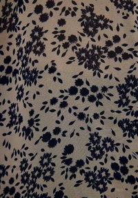 Tejido con estampado floral que presenta flores y hojas en un oscuro tono marino sobre un fondo beige claro. Textura suave, diseño ligero.