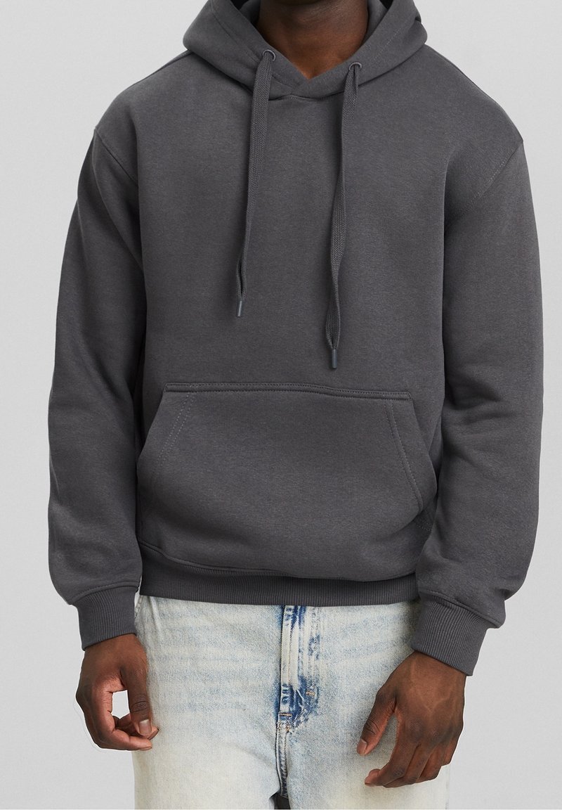 Dark gray hooded sweatshirt with a front pocket, drawstrings, ribbed cuffs, and hem, worn over light blue distressed jeans.