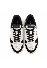 Baskets blancs et noirs avec un design texturé, présentant un bout perforé, des lacets noirs et un talon rehaussé d'or. L'étiquette indique "BONS BAISERS Paris."