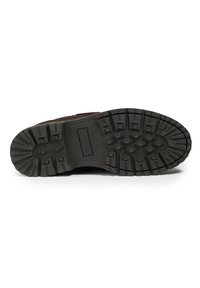 Suela de bota negra de goma con patrones de banda de rodadura profundos y tacos circulares, que cuenta con un talón reforzado, diseñado para ofrecer tracción en diversos terrenos.