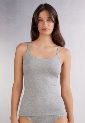 Débardeur gris en tissu doux, avec des bretelles fines et une coupe ajustée. L'encolure est arrondie et il y a une petite étiquette sur l'ourlet.
