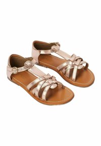 Sandales en rose gold métallique avec un design à lanières croisées, fermeture boucle et bout ouvert. Semelle intérieure lisse en marron et semelle en caoutchouc.