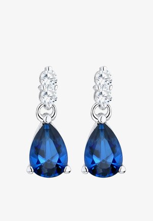 Mėlynų ašarų formos auskarai su trimis skaidriais kubiniais cirkonio akcentais, pagaminti iš sidabro spalvos metalo su blizgiu apdailu.