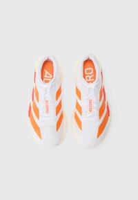 Biele športové topánky s jasne oranžovými a červenými diagonálnymi pruhmi. Vlastnosti zahŕňajú polstrovaný golier a textúrovaný sieťovinový zvršok, označené značkou "ADIZERO".
