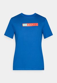 Μπλε βαμβακερό μπλουζάκι με στρογγυλή λαιμόκοψη. Διαθέτει κεντρικό γραφικό με τη λέξη "Nike" και "BARÇA" μέσα σε κίτρινες και κόκκινες ορθογώνιες λεπτομέρειες. Απλός σχεδιασμός.