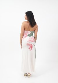 Trägerloses Maxikleid mit floralem Druck in Rosa und Grün auf weißem Hintergrund, aus glattem Stoff gefertigt und mit lockerem Schnitt.