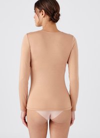 Top a maniche lunghe color nudo con un design aderente e scollo rotondo, realizzato in materiale morbido e elasticizzato, abbinato a slip di colore chiaro.