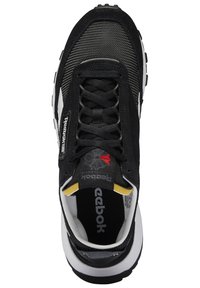 Sorte Reebok-sneakers med mesh-overdel, nubuck-detaljer og hvit mellomsåle. Har sorte snører og gule detaljer på hælen.